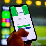 Mobile phone displaying SportyBet app registration screen with Nigerian flag accents